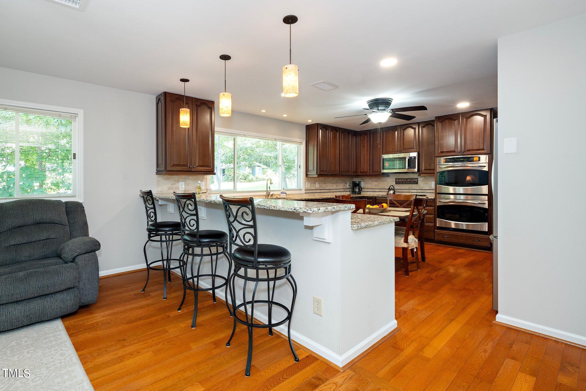 6406 Arnold Road Raleigh, NC 27607 - Photo 23 of 44 a kitchen with stainless steel appliances granite countertop a stove top oven a sink a dining table and chairs with wooden floor
