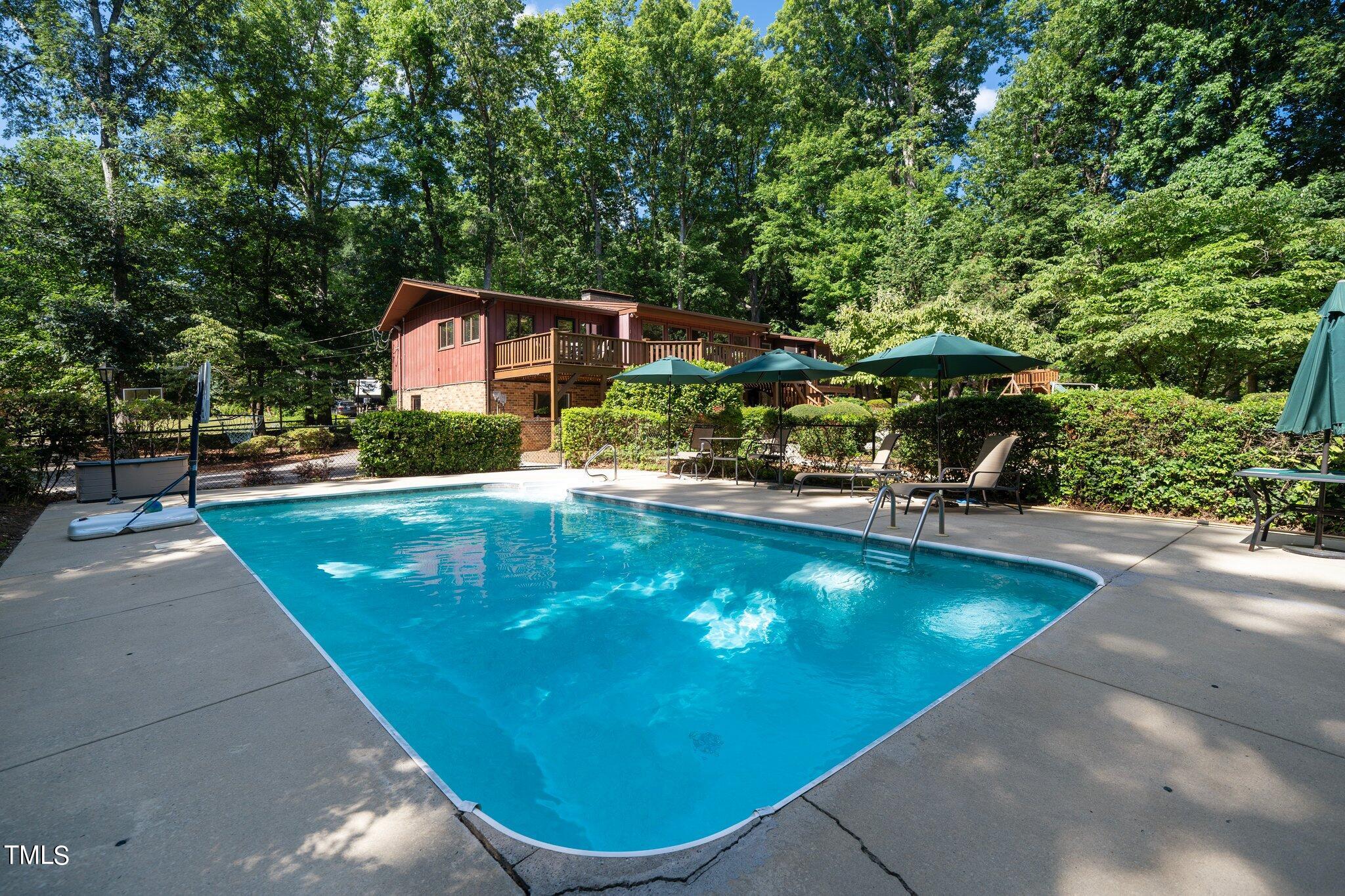 6406 Arnold Road Raleigh, NC 27607 - Photo 8 of 44 a view of a swimming pool with lawn chairs under an umbrella