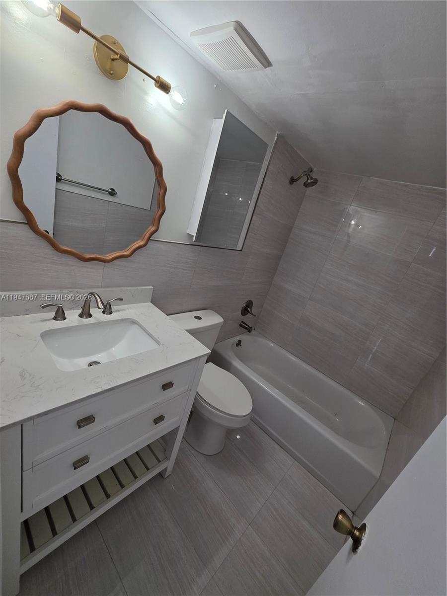 8307 Southwest 142nd Avenue, Unit E108 Miami, FL 33183 - Photo 19 of 22 a bathroom with a sink mirror vanity and toilet