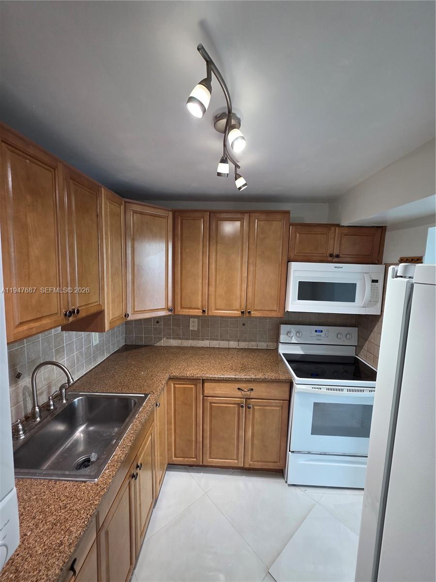 8307 Southwest 142nd Avenue, Unit E108 Miami, FL 33183 - Photo 20 of 22 a kitchen with stainless steel appliances granite countertop a sink and stove