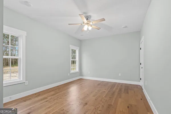 an empty room with wooden floor fan and windows