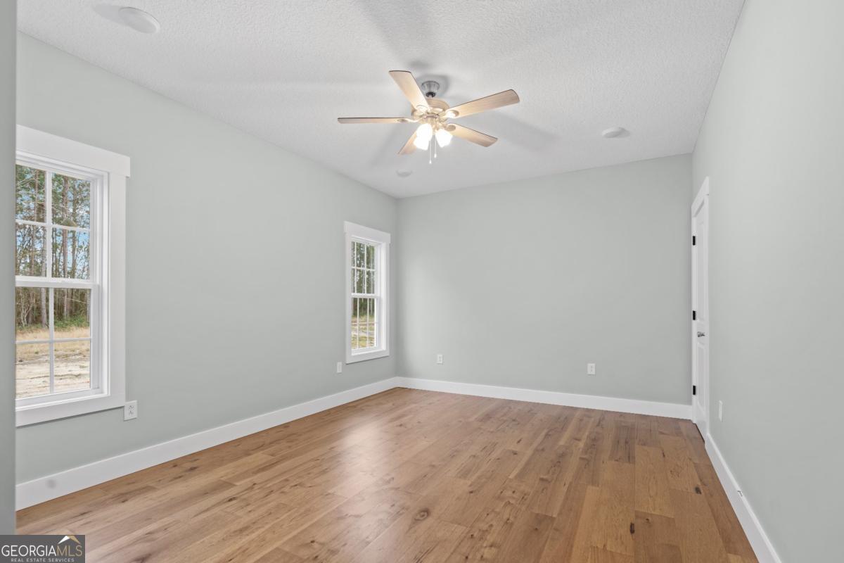 596 Beach Road Baxley, GA 31513 - Photo 13 of 17 an empty room with wooden floor fan and windows