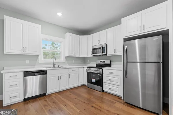a kitchen with cabinets stainless steel appliances a sink and wooden floor