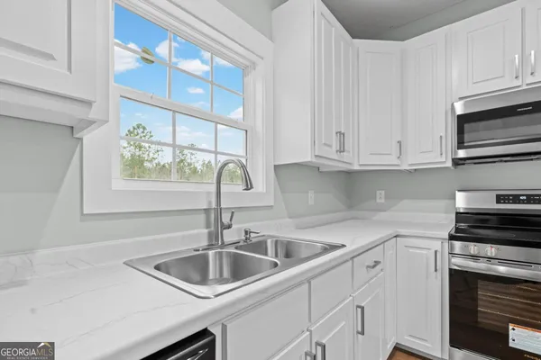 a kitchen with white cabinets a sink and a stove with wooden floor
