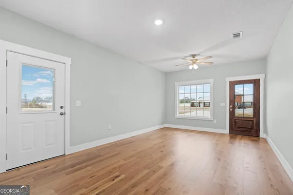 a view of an empty room with wooden floor and a window