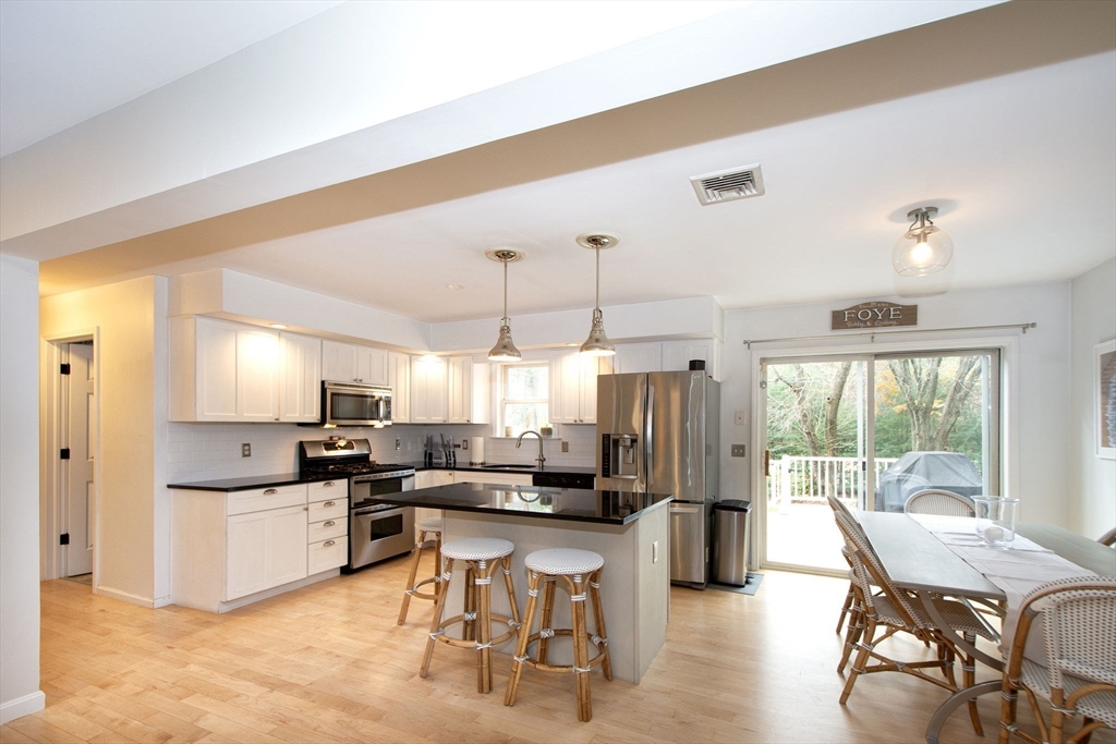 21 Union Street Marshfield, MA 02050 - Photo 11 of 31 a kitchen with stainless steel appliances kitchen island granite countertop a refrigerator a stove a sink a dining table and chairs with wooden floor