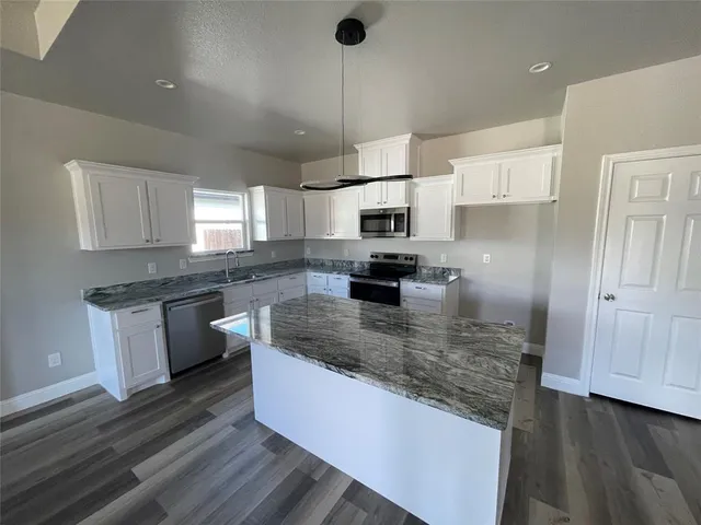 a kitchen with kitchen island granite countertop a sink cabinets and stainless steel appliances