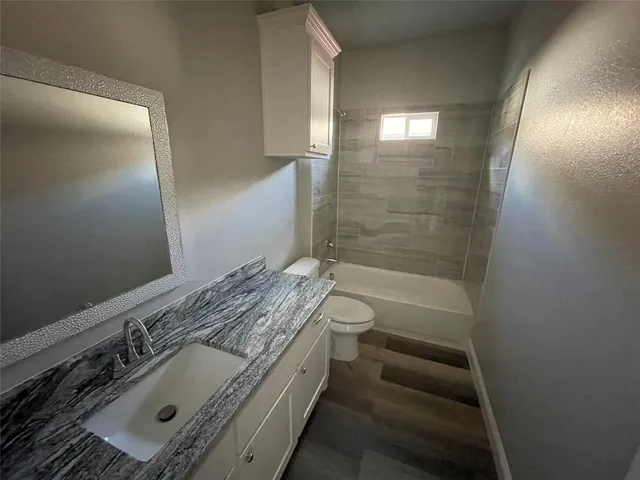 a bathroom with a granite countertop sink a toilet and shower