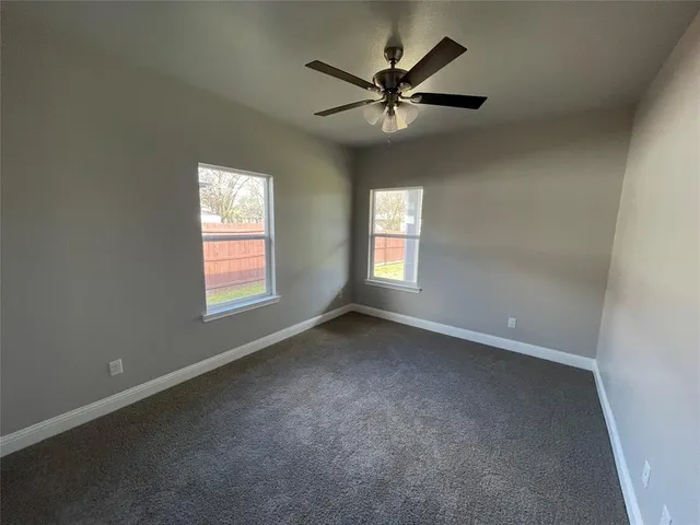 an empty room with windows and fan