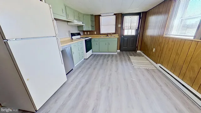 a kitchen with a refrigerator a sink and dishwasher with wooden floor