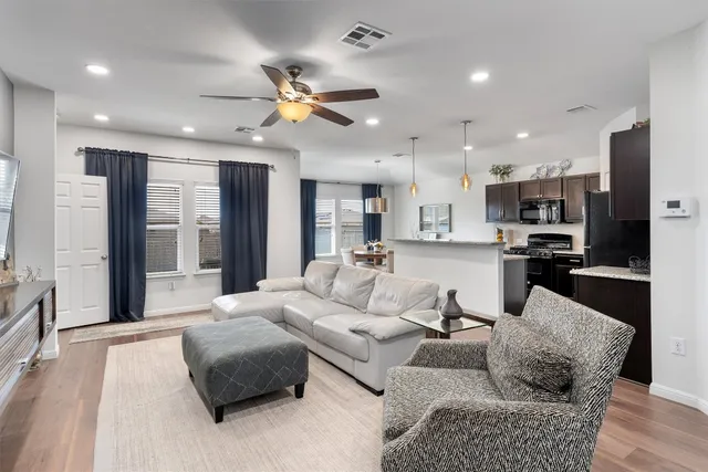 a living room with furniture kitchen area and a chandelier