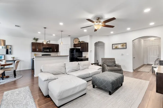 a living room with furniture kitchen view and a chandelier