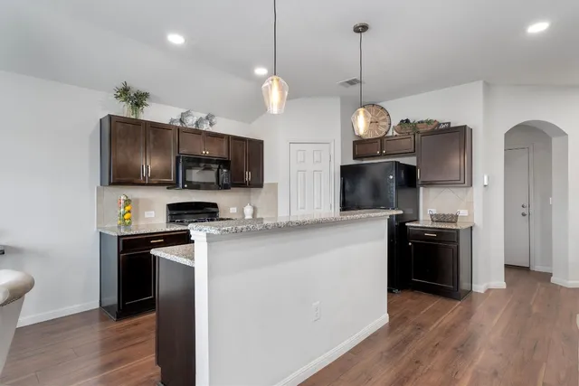 a kitchen with stainless steel appliances granite countertop a refrigerator a stove top oven a sink dishwasher and wooden floor