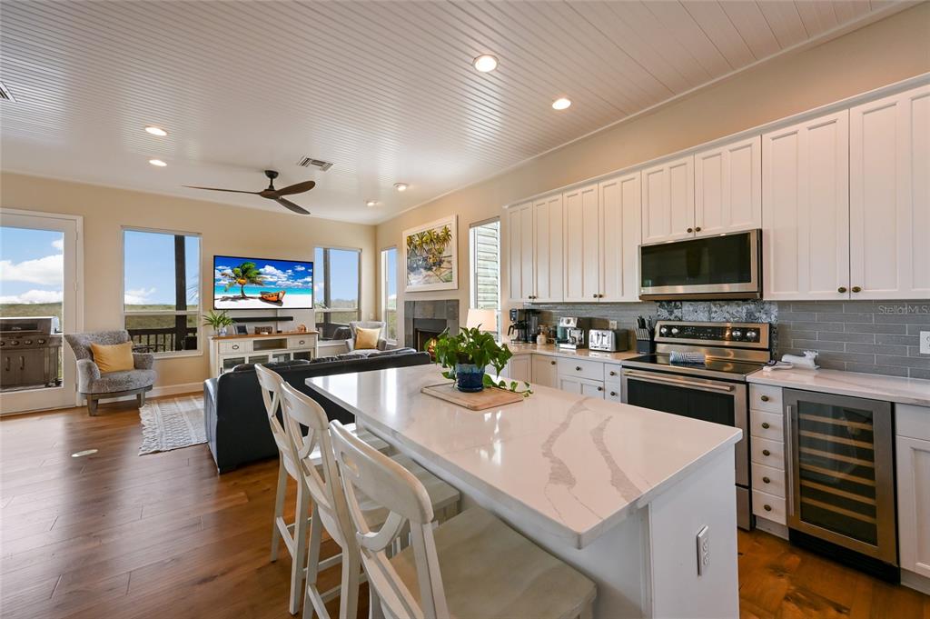7325 Holly Road Terra Ceia, FL 34250 - Photo 10 of 87 a kitchen with stainless steel appliances granite countertop a stove top oven a sink dishwasher a dining table and chairs with wooden floor