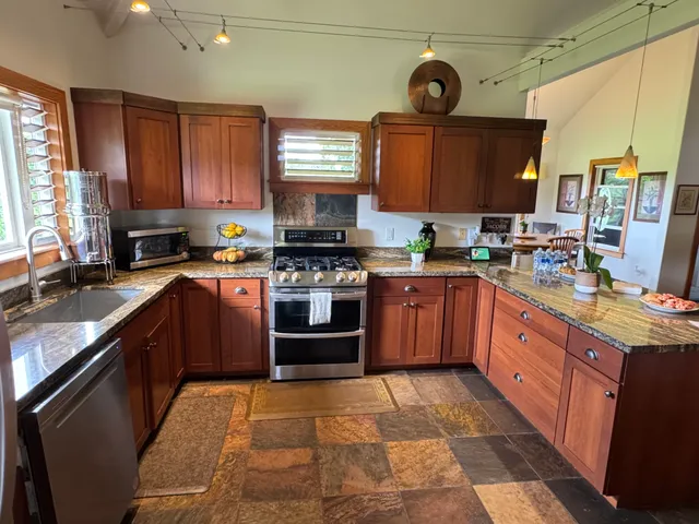 a large kitchen with stainless steel appliances granite countertop a stove sink and cabinets