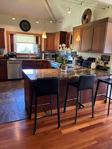 a kitchen with stainless steel appliances granite countertop wooden cabinets a stove a sink and a microwave