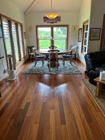 a dining room with wooden floor and large windows