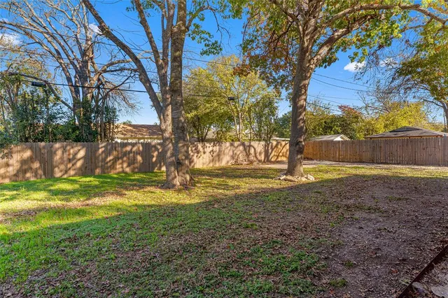 a view of a house with a yard and large tree