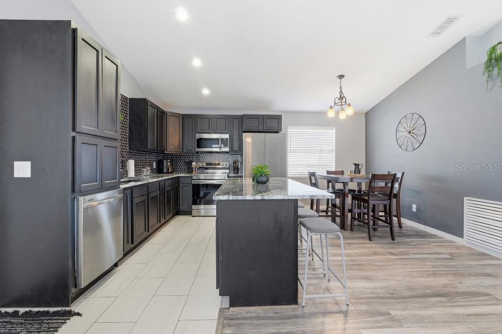 25130 Ensley Road Sorrento, FL 32776 - Photo 6 of 15 a living room with stainless steel appliances kitchen island granite countertop a table chairs and a refrigerator