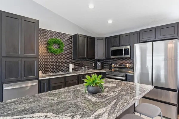 a kitchen with stainless steel appliances granite countertop a sink refrigerator and microwave