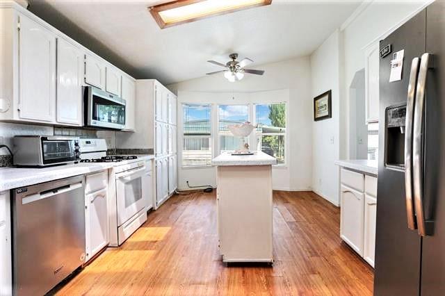 a kitchen with granite countertop a refrigerator a stove top oven a sink dishwasher and white cabinets with wooden floor