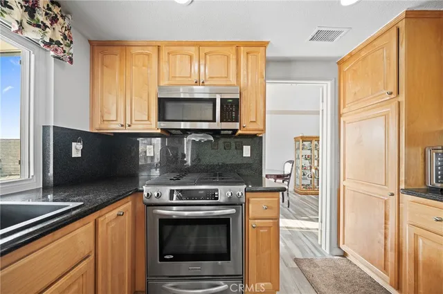 a kitchen with granite countertop a stove top oven microwave and refrigerator