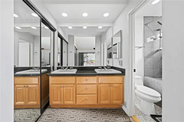 a bathroom with a granite countertop sink a toilet a mirror and shower