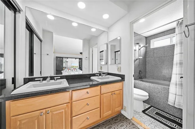 a spacious bathroom with a granite countertop sink toilet mirror and shower