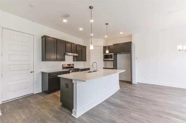 a large kitchen with kitchen island a sink stainless steel appliances and cabinets