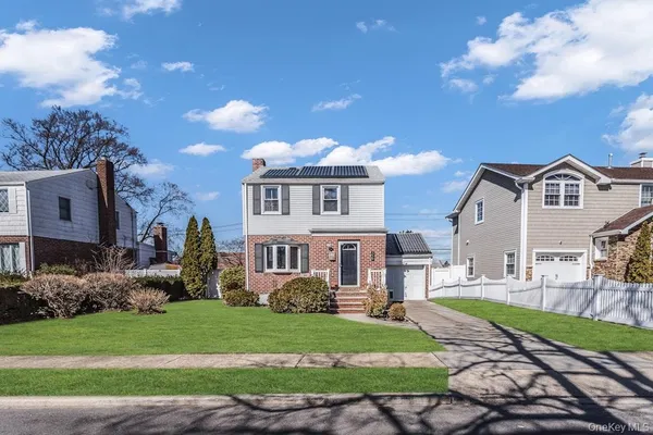 a front view of a house with a yard and trees