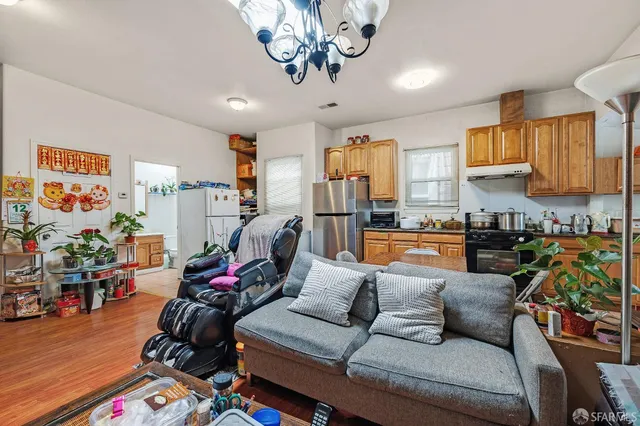 a kitchen with stainless steel appliances granite countertop a refrigerator a sink dishwasher a stove and a dining table with wooden floor