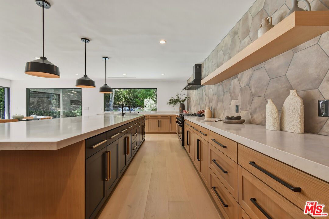 3721 Woodcliff Road Sherman Oaks, CA 91403 - Photo 12 of 35 a large kitchen with stainless steel appliances kitchen island granite countertop a sink and a wooden floor