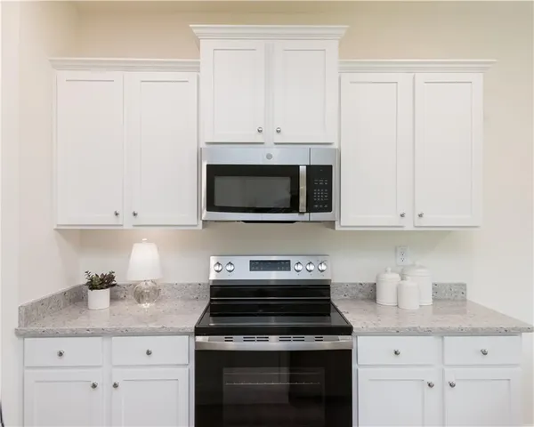 a kitchen with granite countertop white cabinets and stainless steel appliances