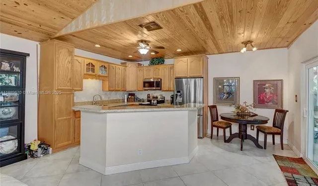 a kitchen with kitchen island stainless steel appliances a stove refrigerator sink and microwave