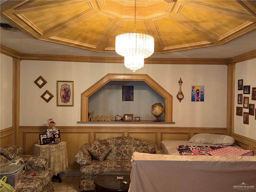 937 Whitewing Street Roma, TX 78584 - Photo 2 of 14 Tiled living area with a decorative wall, wainscoting, suspended lighting, and crown molding