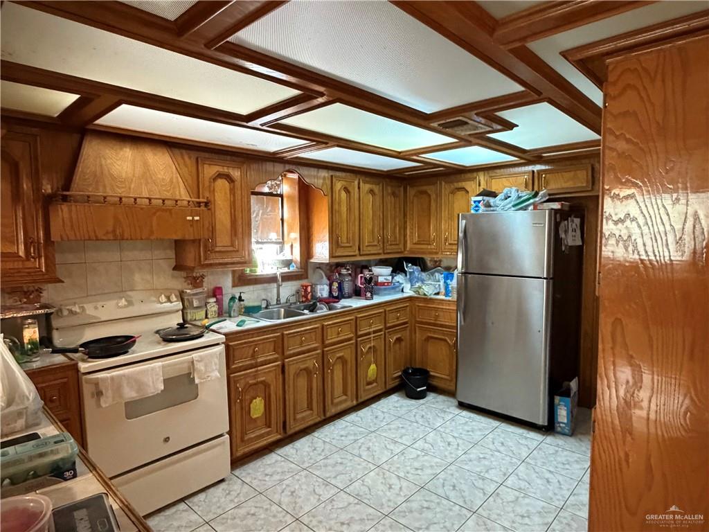 937 Whitewing Street Roma, TX 78584 - Photo 5 of 14 Kitchen featuring wood finish cabinetry, white electric range, freestanding refrigerator, and light countertops