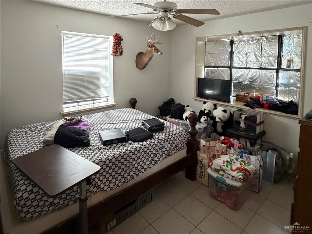 937 Whitewing Street Roma, TX 78584 - Photo 8 of 14 Bedroom with a textured ceiling, light tile patterned floors, and a ceiling fan
