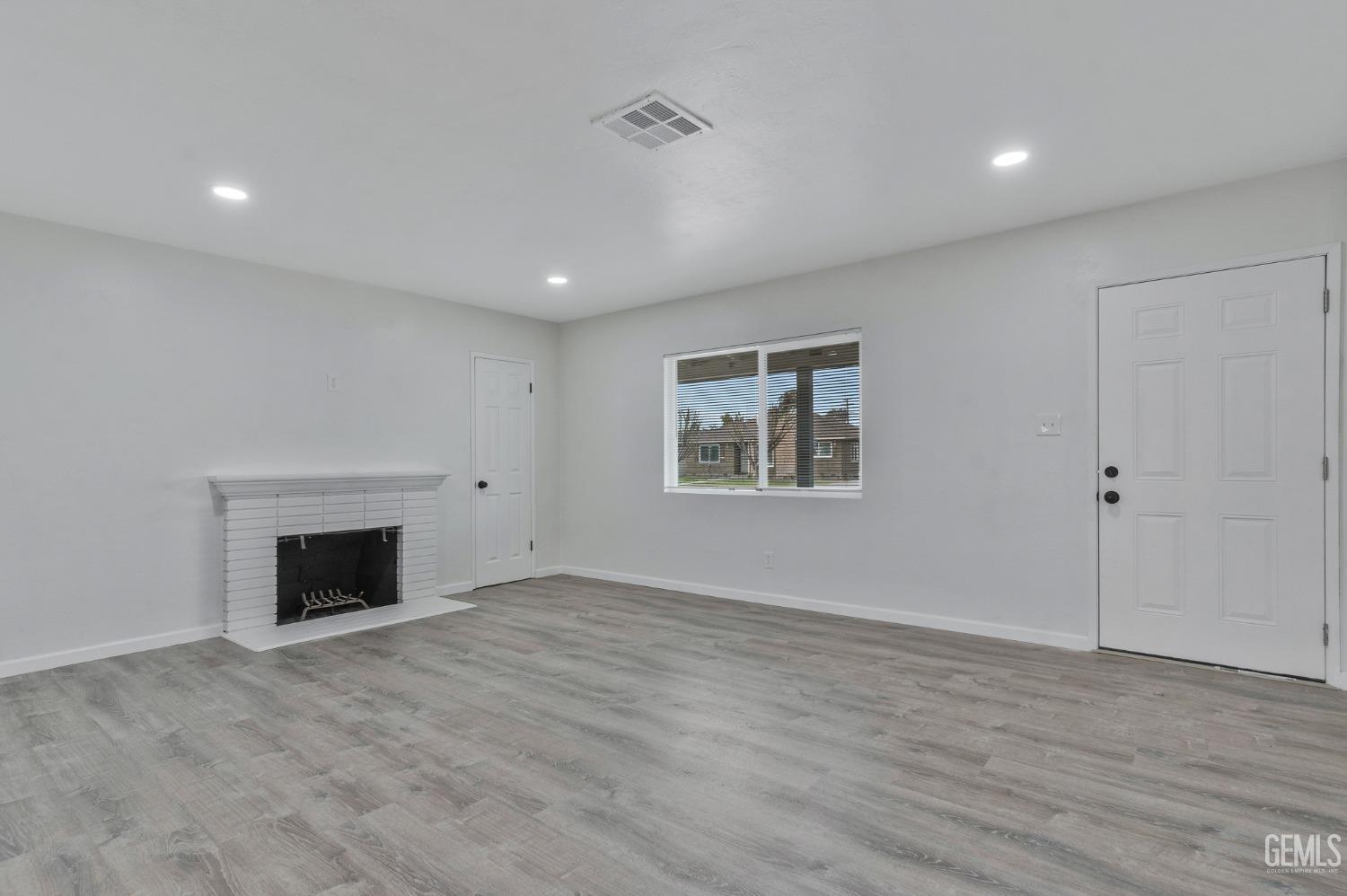 Undisclosed Address Bakersfield, CA 93304 - Photo 4 of 29 an empty room with wooden floor fireplace and windows