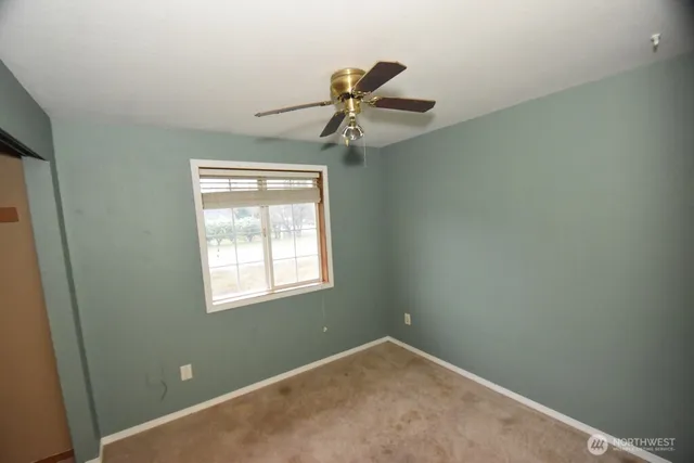 an empty room with a window and a fan