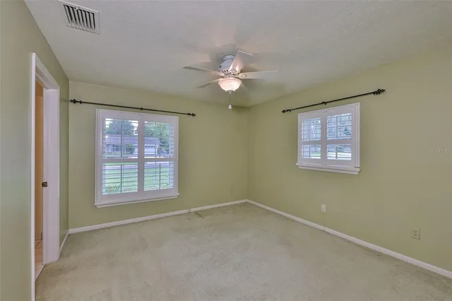an empty room with a window and a fan