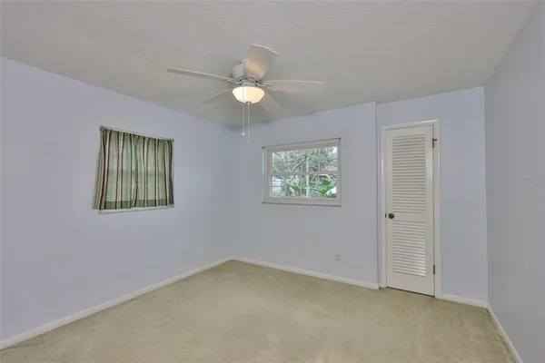 an empty room with windows and fan