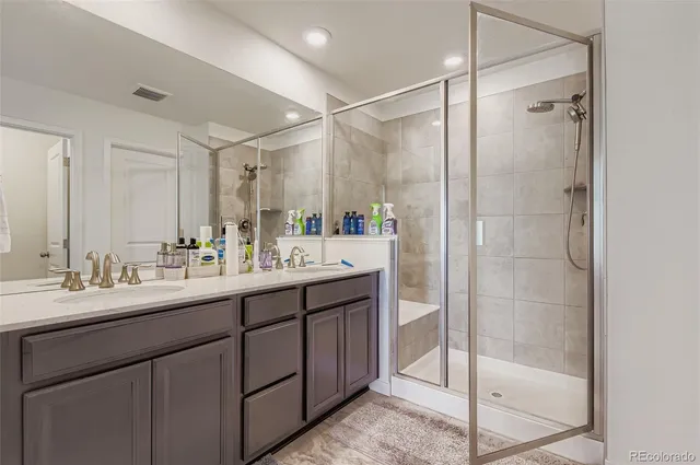 a bathroom with a double vanity sink mirror and shower