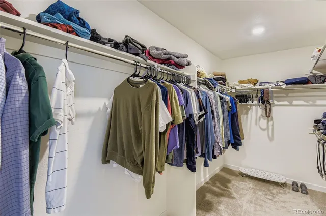 a view of walk in closet with clothes and shoes
