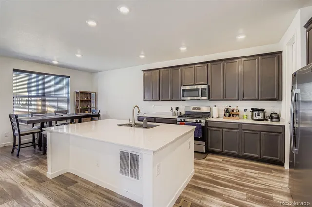 a kitchen with stainless steel appliances granite countertop a stove top oven a sink dishwasher and a refrigerator