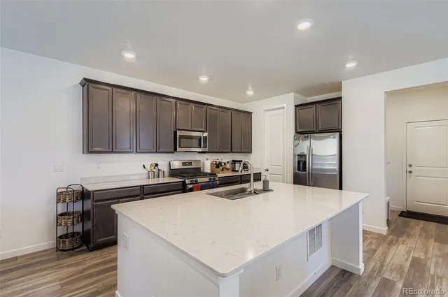 a kitchen with stainless steel appliances a sink stove refrigerator and cabinets