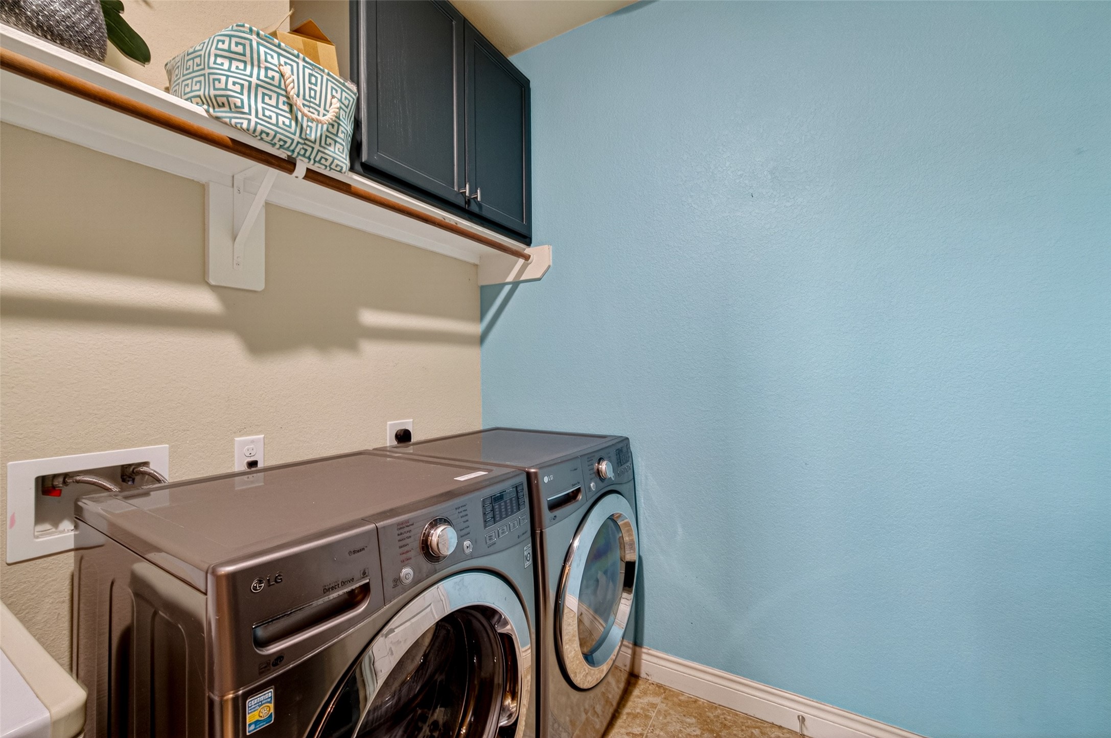 25611 Ellis Ridge Court Katy, TX 77494 - Photo 18 of 49 This photo shows a well-organized laundry room with modern appliances, light blue walls, and a shelf with storage above.