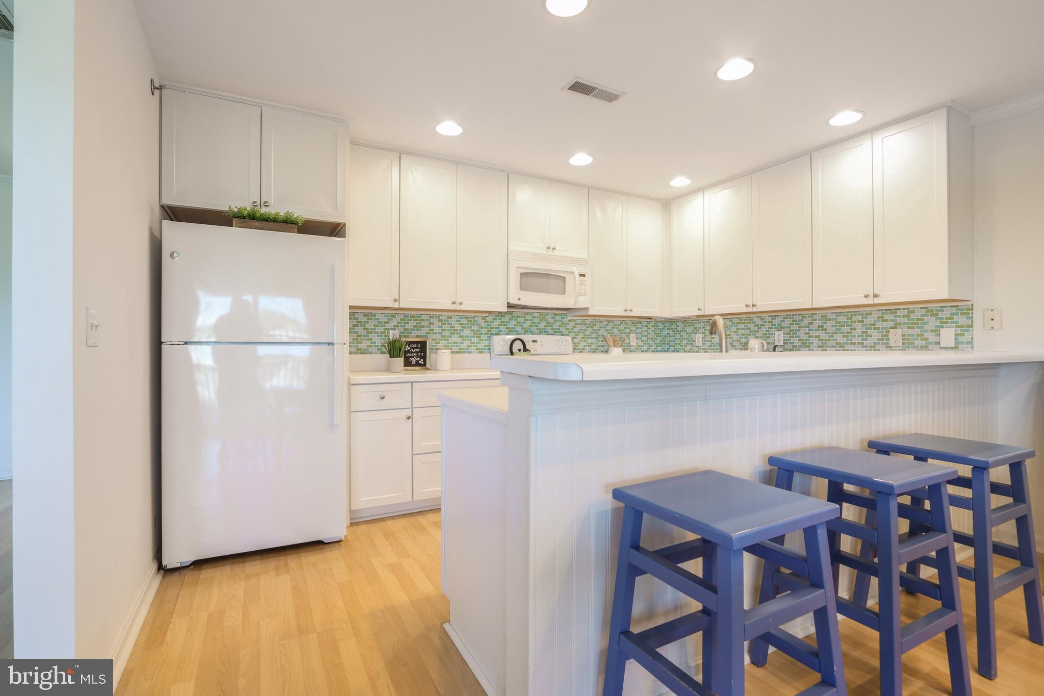 24 Brooklyn Avenue, Unit E Rehoboth Beach, DE 19971 - Photo 21 of 74 a kitchen with kitchen island a stove a refrigerator and a dining table with wooden floor