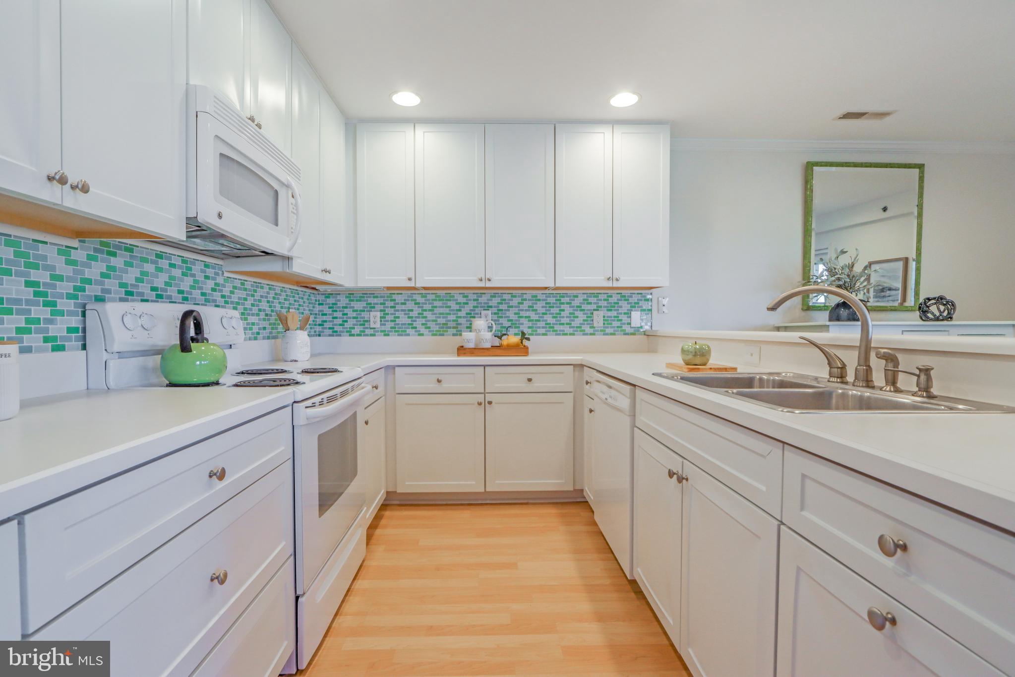 24 Brooklyn Avenue, Unit E Rehoboth Beach, DE 19971 - Photo 23 of 74 a kitchen with a sink dishwasher stove and white cabinets with wooden floor