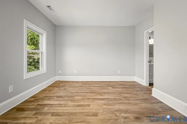 an empty room with wooden floor and entrance
