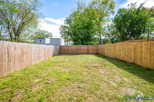 a view of backyard of house with wooden fence